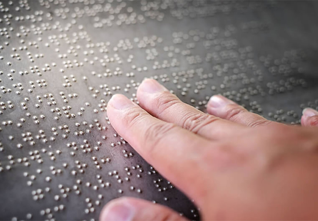 Foto di una mano che legge in braille